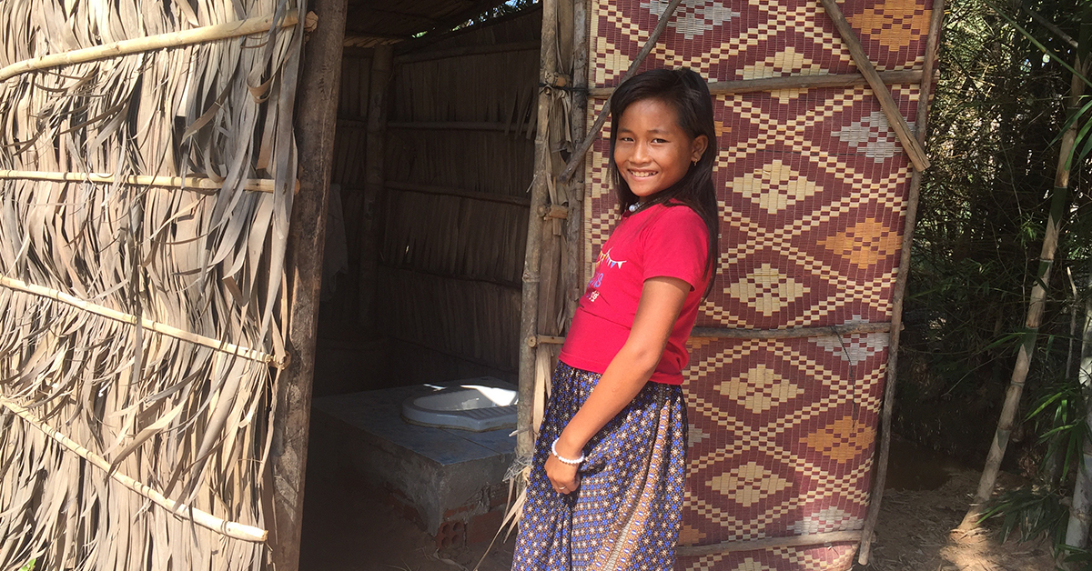 A young girl shows off her newly built toilet in Cambodia