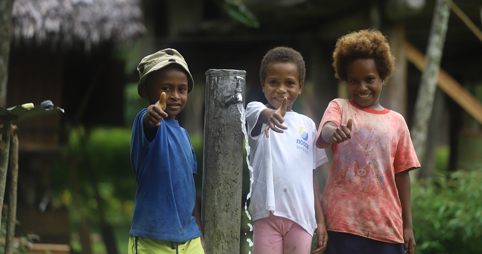 Local children stand with thumbs up next to their new tap stand built in the village, Kairiru Island, East Sepik Province, Papua New Guinea, 2021.